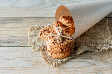 A stack of chocolate chips cookies on baking paper on a light wooden background texture, with copyspace. healthy breakfast concept