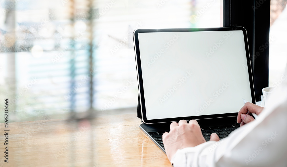 Poster cropped shot of woman hands working on tablet computer with blank screen while sitting at counter ta