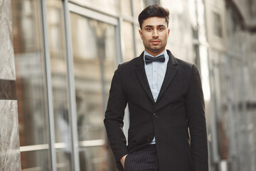 Fototapeta premium Handsome man in a black suit. Businessman standing outdoor.
