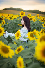 Obraz na płótnie Canvas Happy enjoy summer girl in sunflower field in spring. Asian young woman joyful and smiling at sunset time