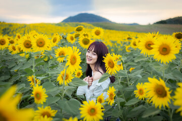 Fototapeta na wymiar Happy enjoy summer girl in sunflower field in spring. Asian young woman joyful and smiling at sunset time