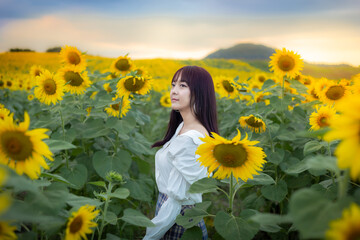 Happy enjoy summer girl in sunflower field in spring. Asian young woman joyful and smiling at sunset time