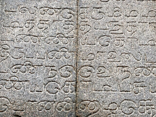 Inscriptions on the ancient temple stone walls. Ancient stone carving. Old stone wall texture. Tamil inscriptions in historical temple walls. Carved inscription in Varadharaja Perumal temple.