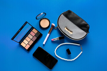 Composition with cosmetics, bag and mobile phone on color background