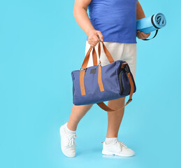 Sporty senior man with bag and yoga mat on color background