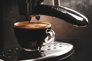 Modern coffee machine with cup of hot beverage on dark background, closeup
