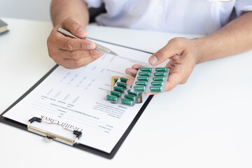 A doctor or nurse who writes medical reports or prescription lists on a clipboard on a hospital desk.