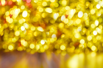 Gold bokeh background. Texture with shining blurred lights in yellow, red and silver. Abstract Christmas festive background. Blurry lights of gold color.