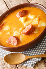 Tasty Hungarian potato soup with sausage and sour cream close-up in a plate on the table. Vertical