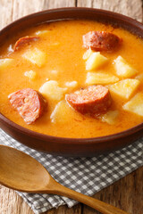 Hungarian Krumplileves potato soup with sausages close-up in a plate on the table. Vertical