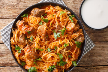 Sauerkraut stew with pork and paprika close-up in a plate on the table. horizontal top view from...