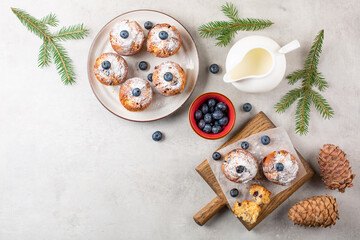 Festive christmas breakfast with blueberry muffins decorated with fresh blueberries and powdered sugar, milk on light grey table , decorated with fir tree branches.  Copy space. Top view.