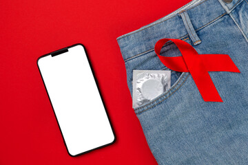 Jeans with a condom in the pocket and a red ribbon. Close up. Red background. Flat lay. Mock up. The concept of world AIDS day and safe sex