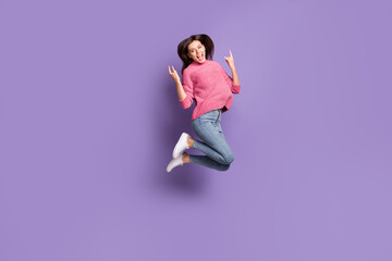 Full length body size photo of jumping high female rocker showing heavy metal gesture isolated on vivid violet color background