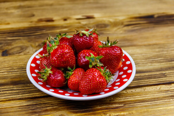 Fresh strawberry in a plate on a wooden table