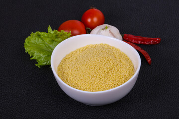 Raw couscous in the bowl served salad leaves, tomato and pepper