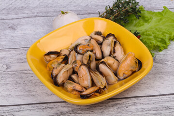 Pickled mussels in the bowl served pepper, garlic and salad