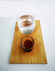Isolated close-up shot of a double shot of espresso in glass, iced water on wooden tray, isolated object on the white background.