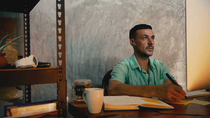 Man sitting at home wearing headphones communicating by video call .Businessman speaking looking at...