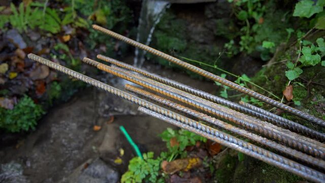 Close up of rusty reinforcement rod, falling water in the background