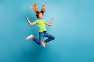 Photo portrait of ecstatic girl celebrating jumping up isolated on pastel blue colored background
