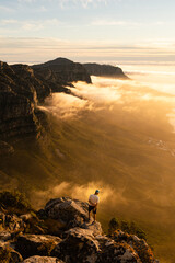 A trail runner enjoying the sunset from a mountain top - 395230422
