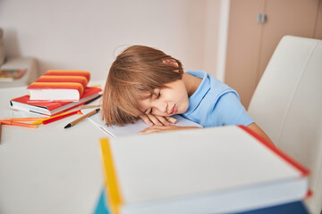 Adorable child falling asleep while studying at home