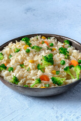 Vegan rice in a pan close-up with copy space. Rice with broccoli, carrot, green peas