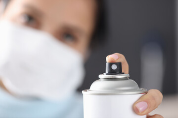 Woman in protective mask splashes from spray paint can. Spray paint application