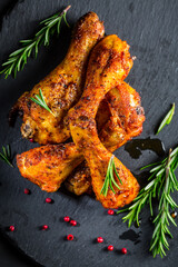 Hot spicy chicken legs with herbs on black background