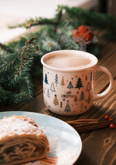 Obraz na płótnie Canvas Closeup of a strudel on a Christmas plate near cinnamon sticks and hot chocolate. Christmas breakfast 