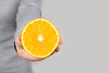 Hand with half orange on grey background.