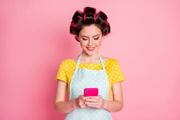 Portrait of attractive cheerful focused maid housekeeper using gadget browsing news media isolated on pink pastel color background