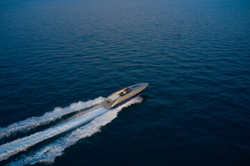 Large speed boat moving at high speed side view. Drone view of a boat  the blue clear waters at...
