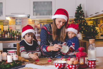 Sweet toddler child and his older brother, boys, helping mommy preparing Christmas cookies at home