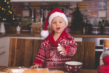 Sweet toddler child and his older brother, boys, helping mommy preparing Christmas cookies at home .