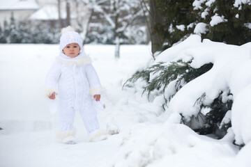Fototapeta na wymiar Cute little toddler boy, playing outdoors with snow on a winter day