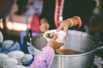 Volunteers scooping the food to share with the needy : concept of free food to beggars