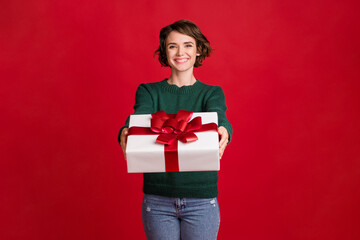 Photo of positive pretty lady give you x-mas present good mood toothy smile isolated on red color...