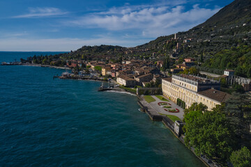 Fototapeta na wymiar Panoramic view of the sights on Lake Garda Italy. Aerial view of architecture on Lake Garda. Ancient villa on Lake Garda in the background Alps and blue sky.