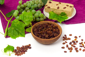 Yellow raisins, bunch of grape with leaves and halva on table cloth. Organic food and drinks concept