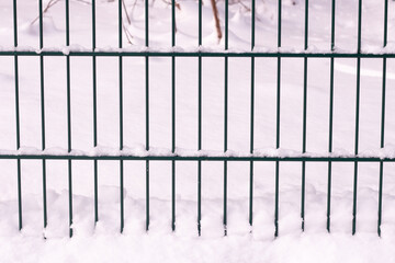 metal mesh fence with fluffy snow