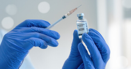 coronavirus covid-19 vaccine in bottle with syringe in hand of research scientist