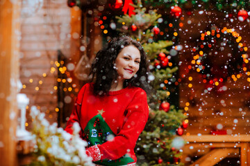 Woman posing on the open wooden terrace with Christmas decoration and snowing.