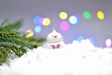 cute edible snowman on the snow and christmas tree branch. bokeh lights. holiday selebration and...