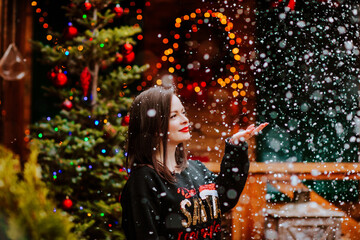 Woman posing on the open wooden terrace with Christmas decoration and snowing.