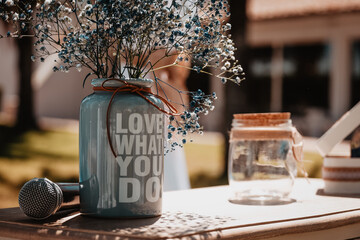 Table decorated for a wedding with flowers and a vase with a motivating phrase.