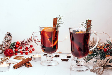Two glasses of hot homemade mulled wine with oranges and rosemary in a New Year's atmosphere