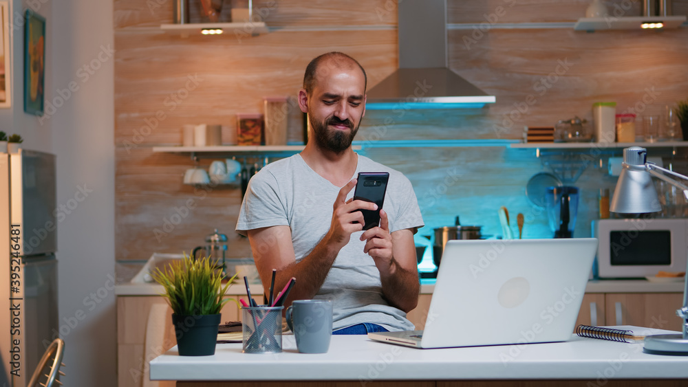 Poster freelancer taking break and searching on phone sitting on kitchen table working from home. busy focu