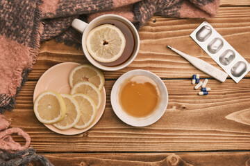 Top view Natural remedies for flu lemon and honey with cup of hot tea on a wooden table thermometer and pills 